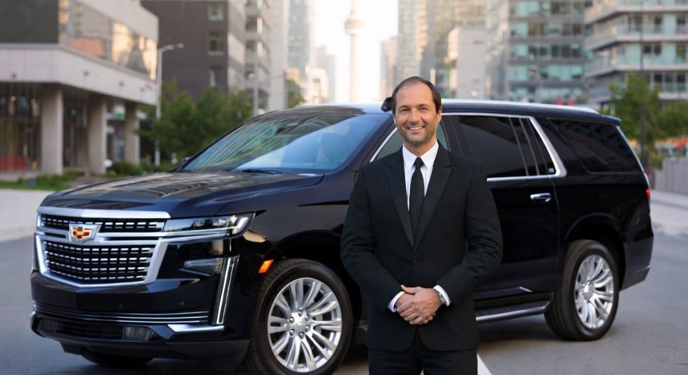 Chaueur in formal business attire standing beside a detailed luxury SUV