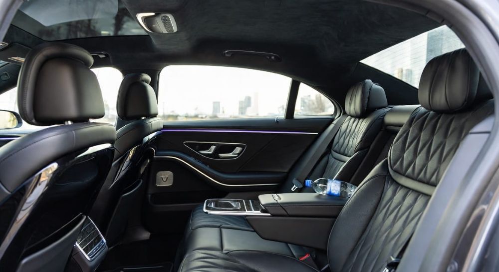 Interior of a luxury sedan with privacy partition, representing confidential corporate travel