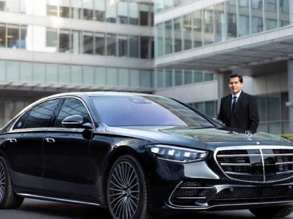 Chauffeur standing beside black Mercedes S-Class sedan outside corporate building - Executive Car Service Toronto