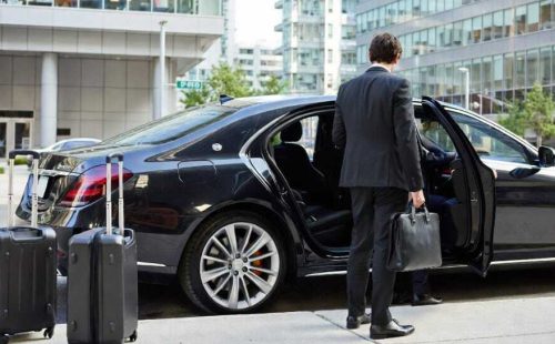 Businessman with briefcase entering black Mercedes sedan with luggage on sidewalk - Executive Sedan Service Toronto