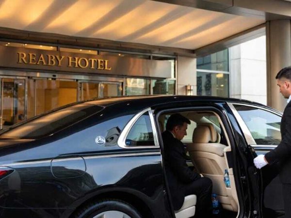Chauffeur in white gloves opening luxury sedan door at hotel entrance - Luxury Car Service Toronto