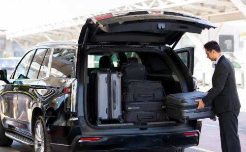 Chauffeur loading multiple suitcases into black luxury SUV trunk at airport - Luxury SUV Service Toronto