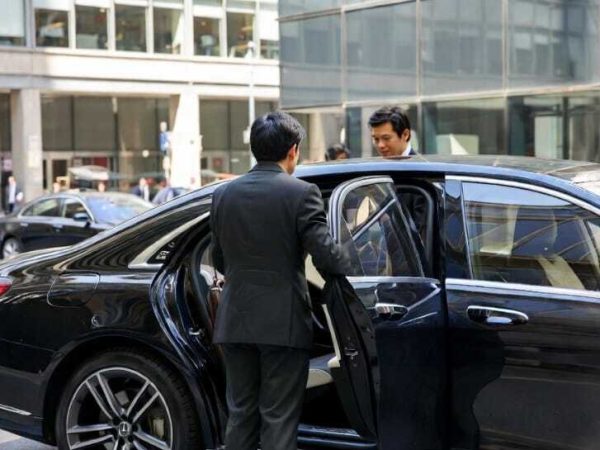 Chauffeur holding car door open for businessman entering black sedan - Town Car Service Toronto