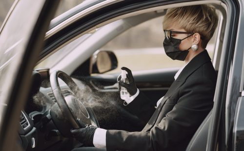 Businesswomanin a car. Lady use a antiseptic. Person in a mask. Coronavirus theme.